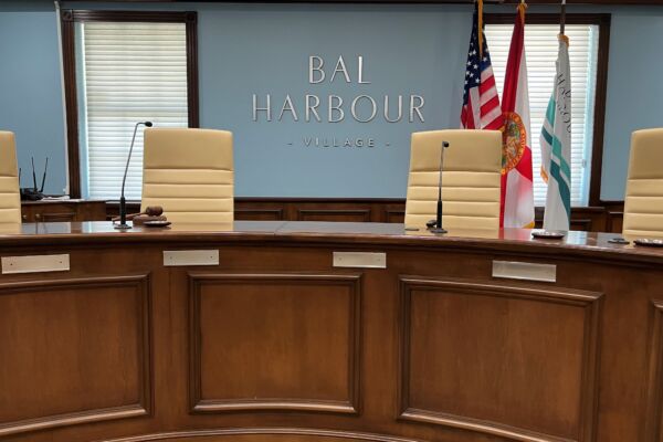 Dais with empty chairs and Bal Harbour logo on wall
