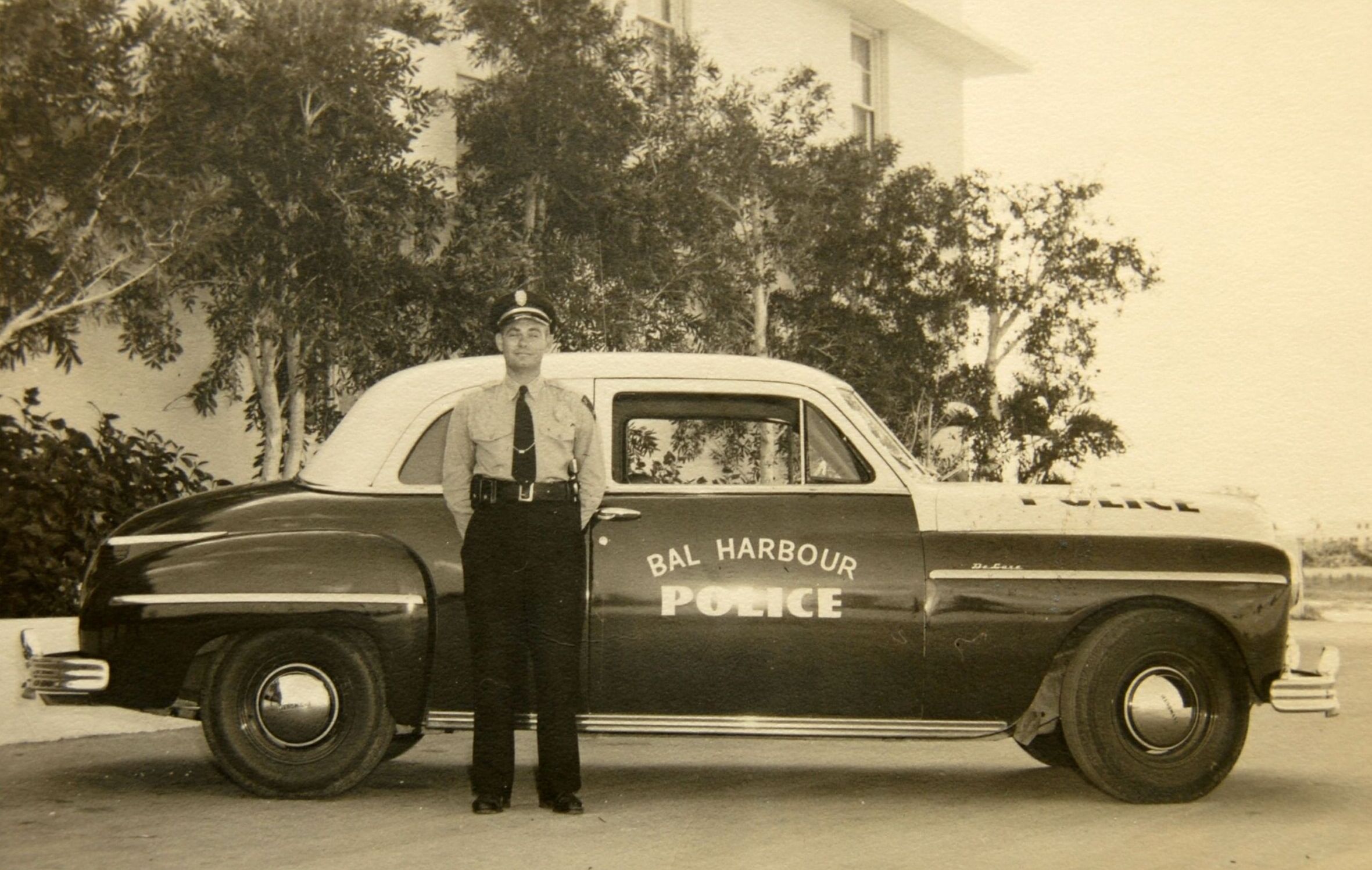 An old photo of a police officer in front of his car