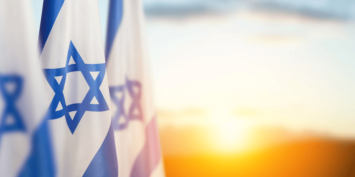 Flags of Israel with the sun rising in the background.