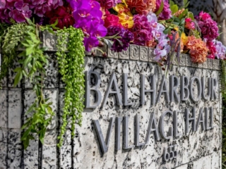 COMPRESSEDFleursDeVilles2024_117 (1) The Bal Harbour Village Hall sign with flowers overflowing the top of it in a multitude of colors and types.