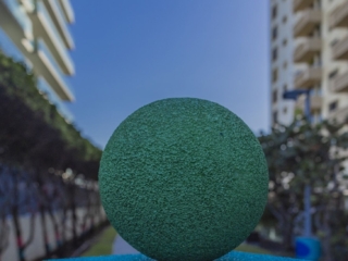 DIC8Compressed One of Artist Andreina Ron Pedrique's sculptures; a green ball over a blue square. The buildings and blue sky of Bal Harbour in the distance.