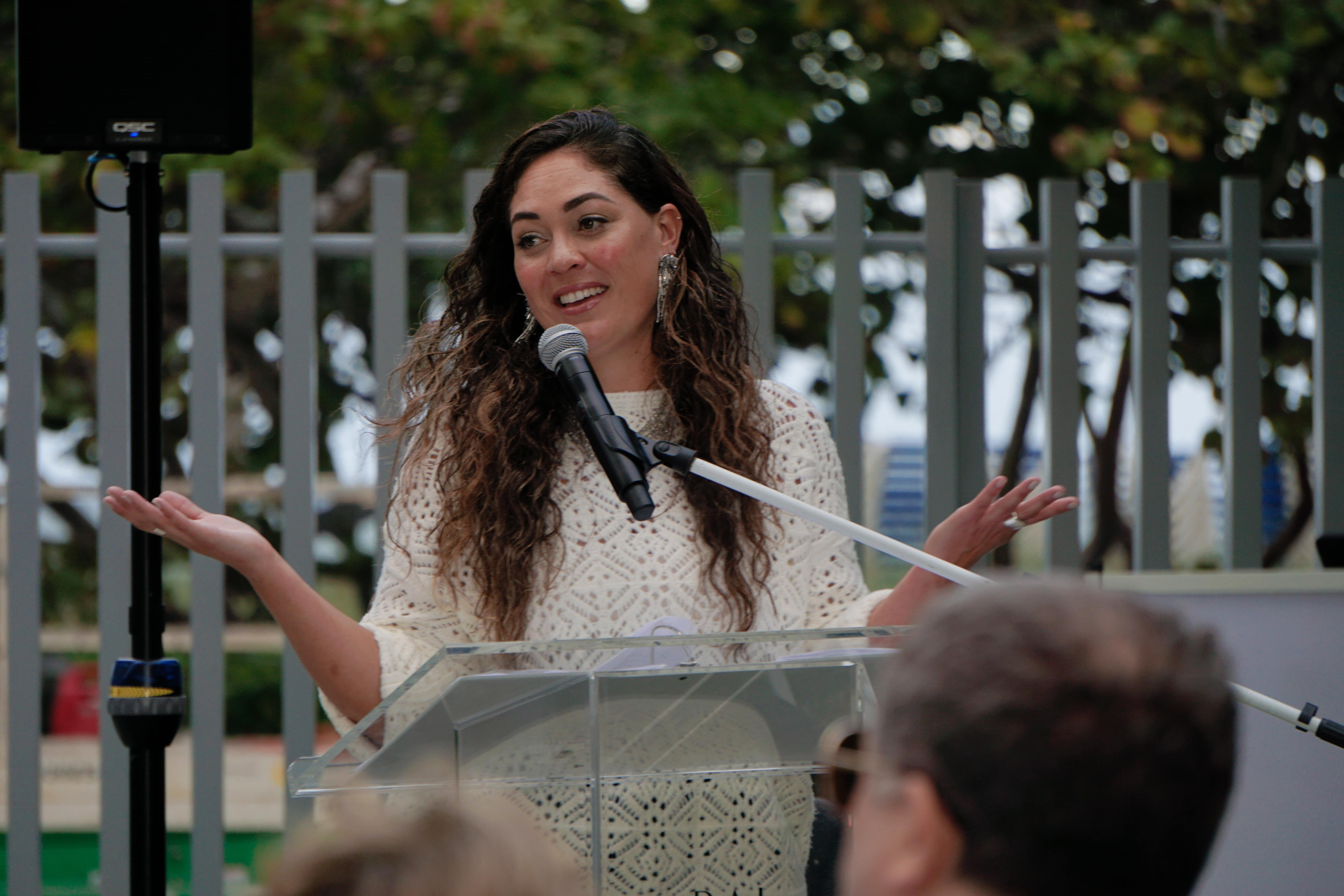 A close-up of Artist Andreina Ron Pedrique speaking for a crowd into a microphone.