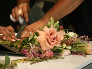 flower frame workshop-COMPRESSED2 A close-up image of a bouquet of flowers being wrapped and made on a table.