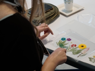 flower frame workshop-COMPRESSED5 A woman's hands moving and perfecting her floral frame, set on a white table.